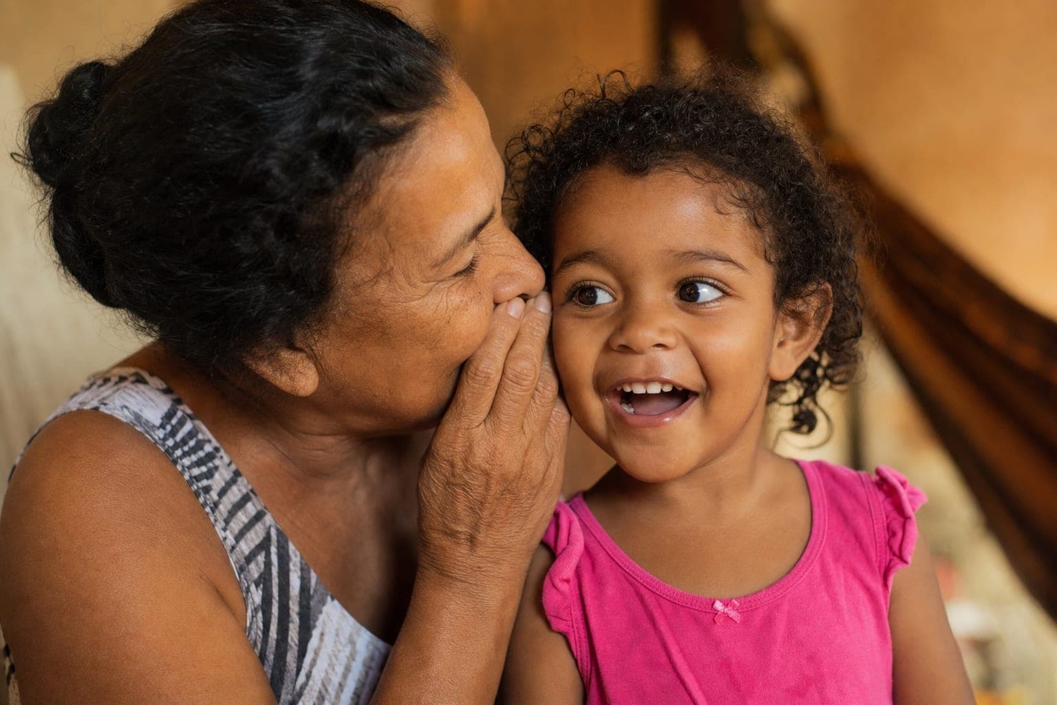 Avó cochichando no ouvido de uma criança sorridente