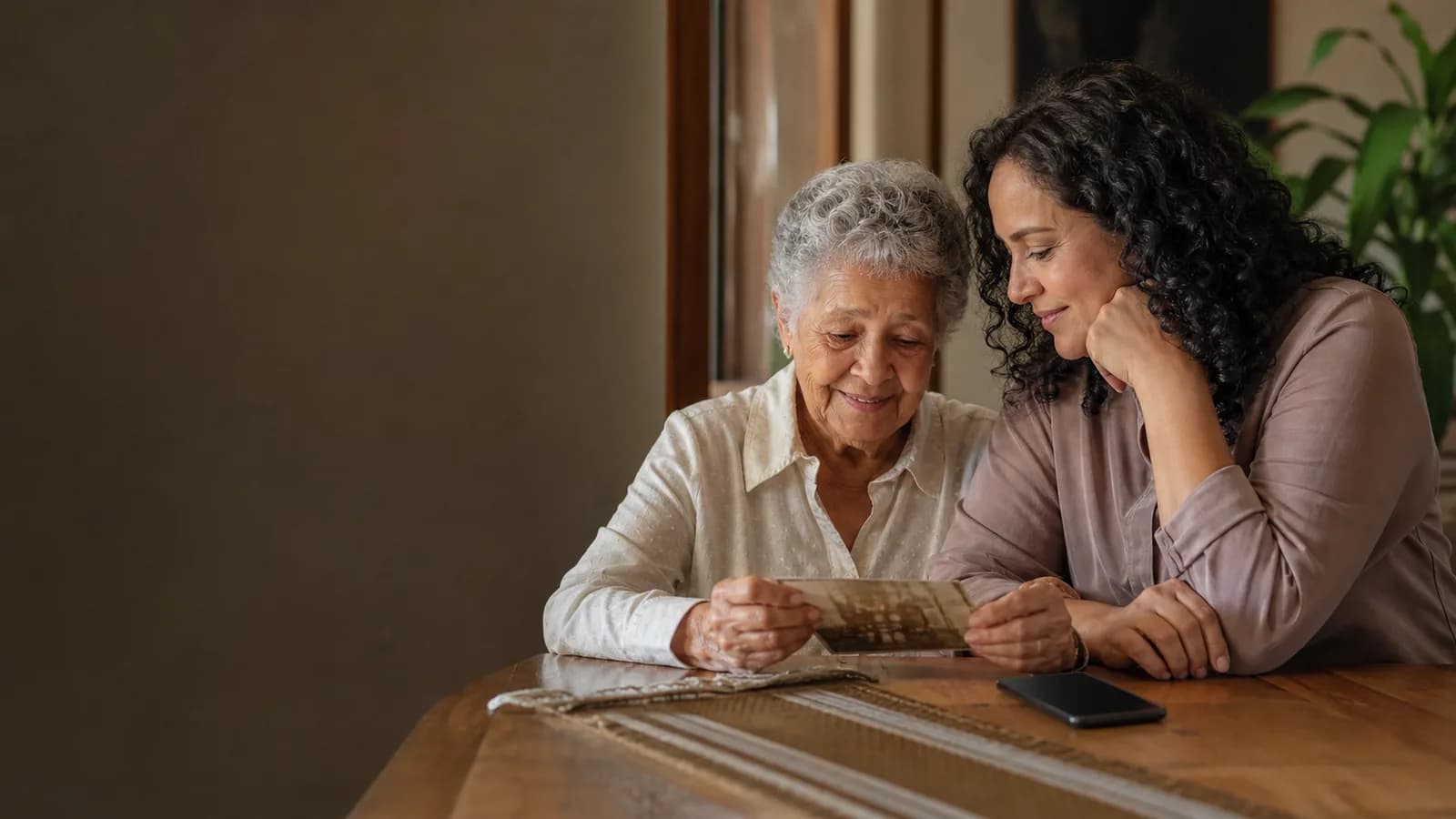 Mãe idosa e filha adulta conversando sobre uma fotografia antiga.